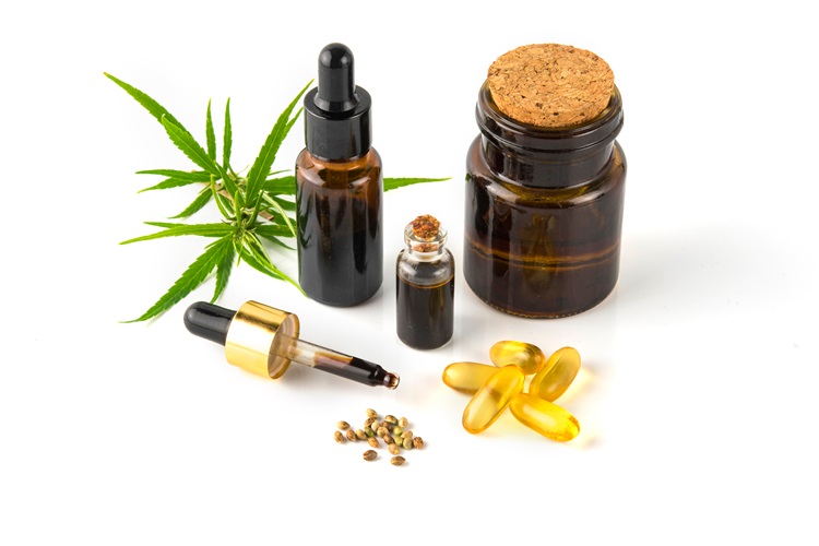 THCO-Produkte - Öl in einer kleinen Glasflasche, Glas mit Cannabisblättern und -samen